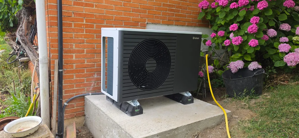 Unidad exterior de aerotermia instalada en el jardín de una vivienda
